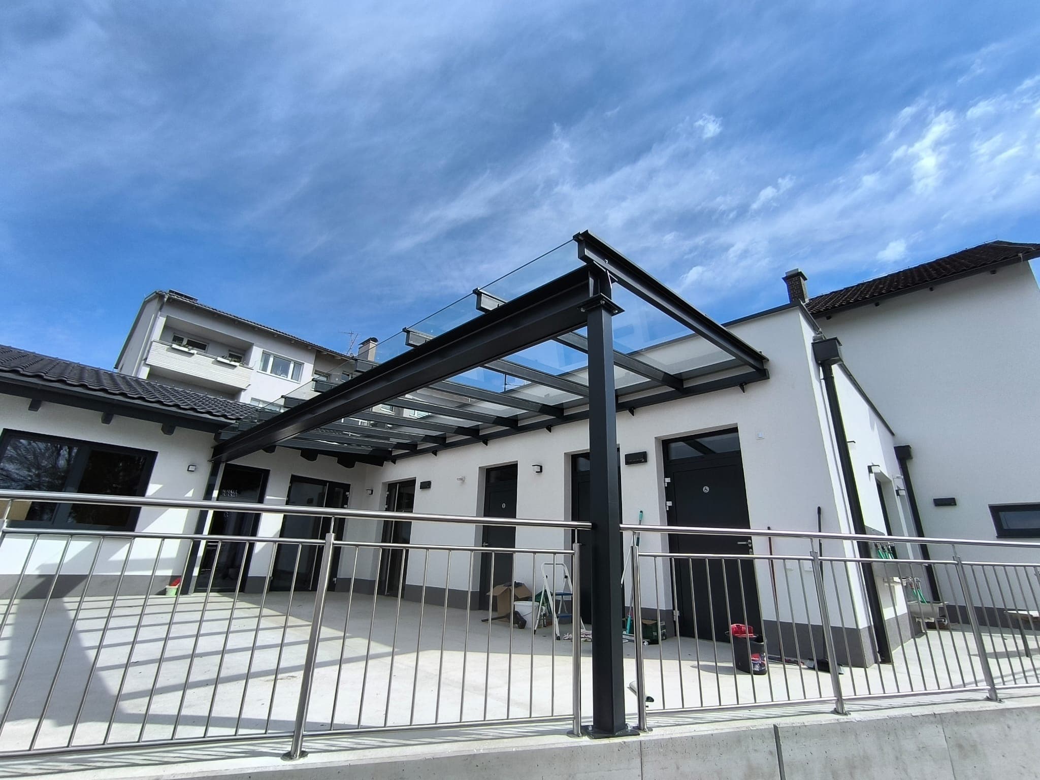 Terrassenüberdachung mit dunkler Metallkonstruktion und Glasdach