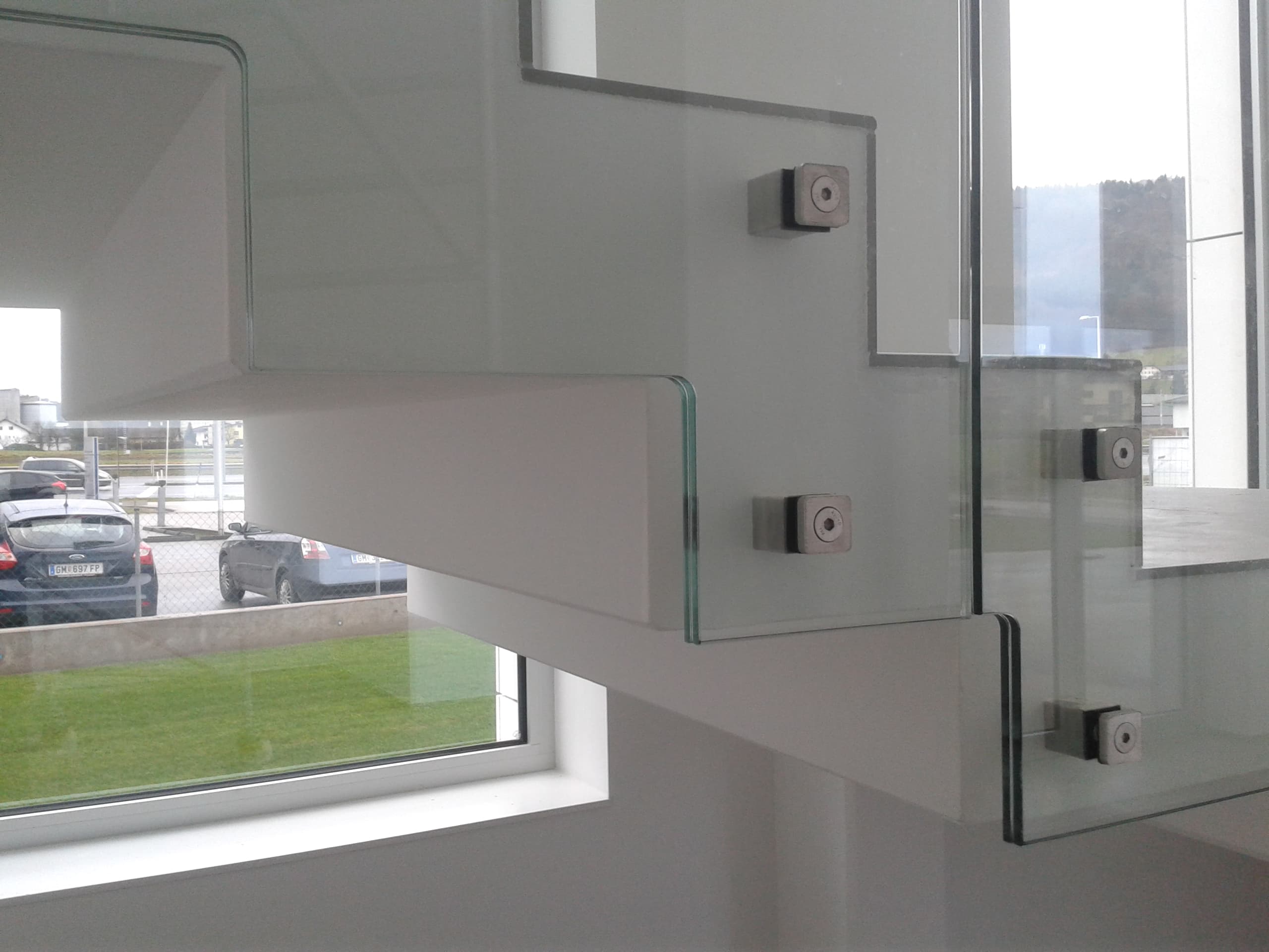 Detail eines Glasgeländers mit abgestuften Kanten und Metallbefestigungen